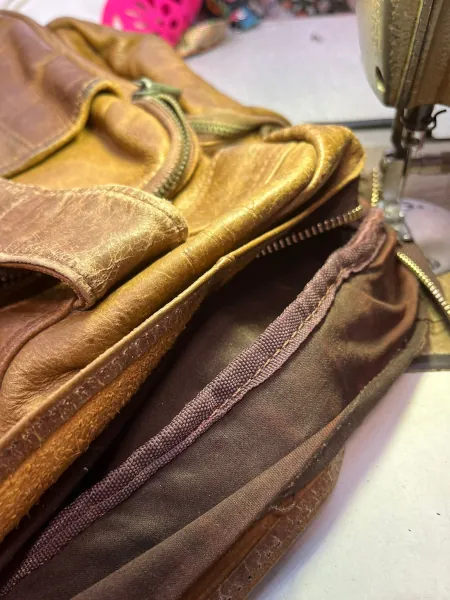 After removing the worn zipper, the new metal zipper was being sewn onto the leather bag.