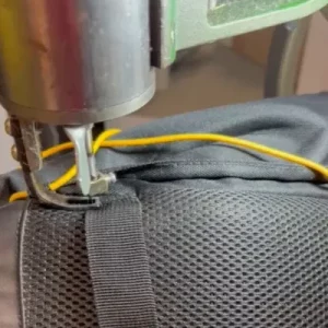 Sewing of nylon strap onto a backpack.