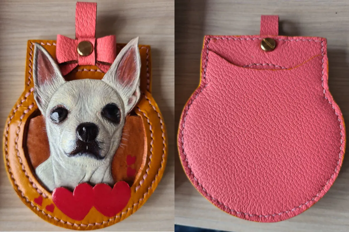 Photo of a leather tag design of a white dog with pointy ears. The right side shows a pink leather back of the leather tag.