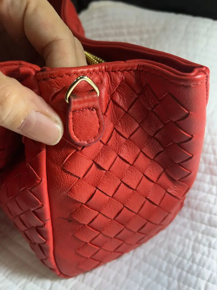 Completed sewing the triangular ring onto the red leather handbag.