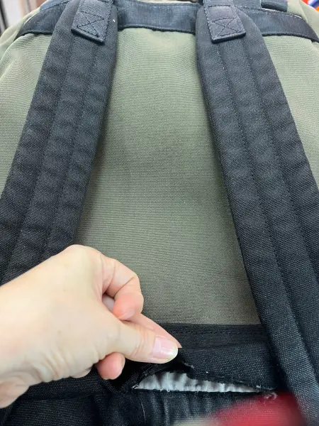 A olive green fabric backpack was torn at the lower part of the bag.