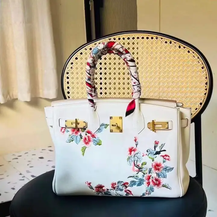 Image shows a white leather marquage handback with flowery and bird design painted on.