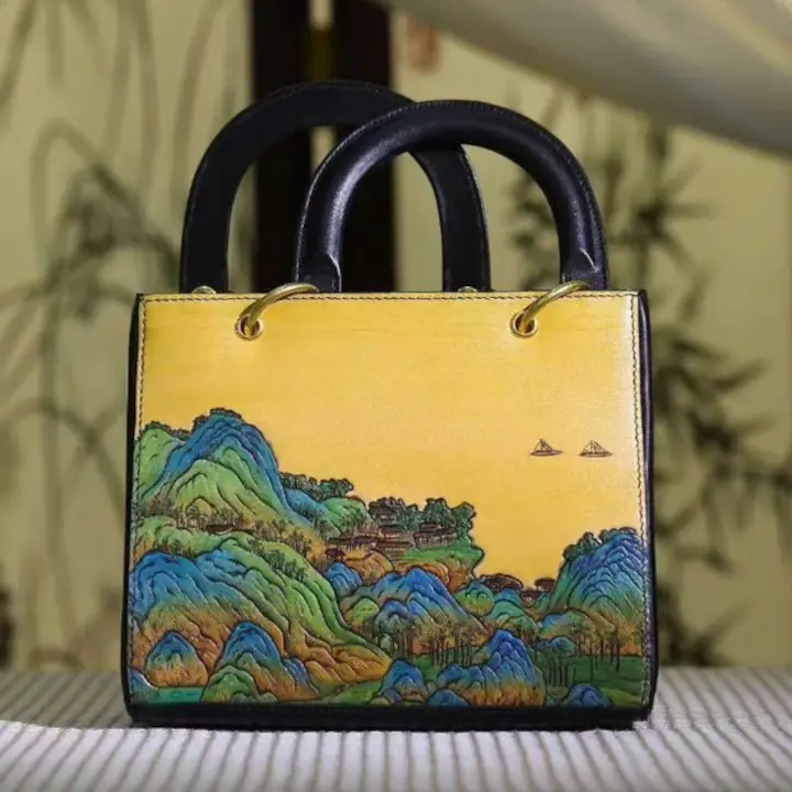 Image shows a yellow leather marquage handback with a hilly scenery design painted on.