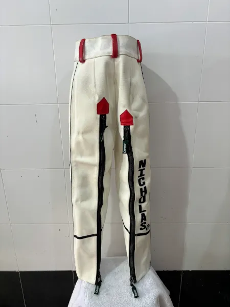 Air rifle shooting trousers with zippers, personalized with the name 'Nicholas' printed on the leg, featuring red and black accents designed for competitive shooting attire.