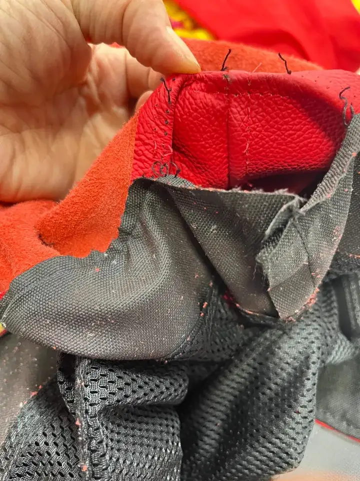 Close-up of red Ducati motorcycle jacket interior, showing intricate alteration stitches and fabric layers.