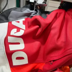 Red Ducati motorcycle jacket being altered on a sewing machine for a more tailored fit.